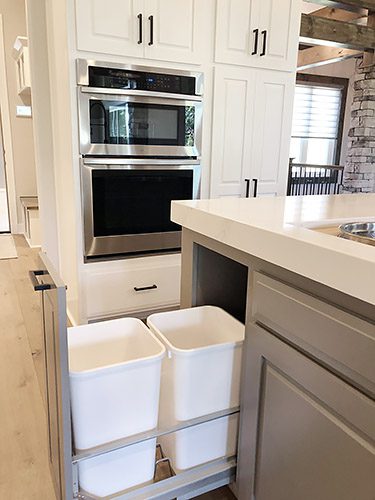 A kitchen with two trash cans in the middle of it.