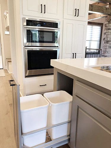 A kitchen with two trash cans in the middle of it.